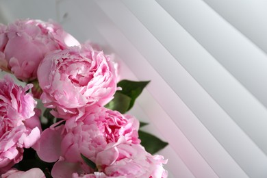 Photo of Bouquet of beautiful peonies near window, closeup. Space for text