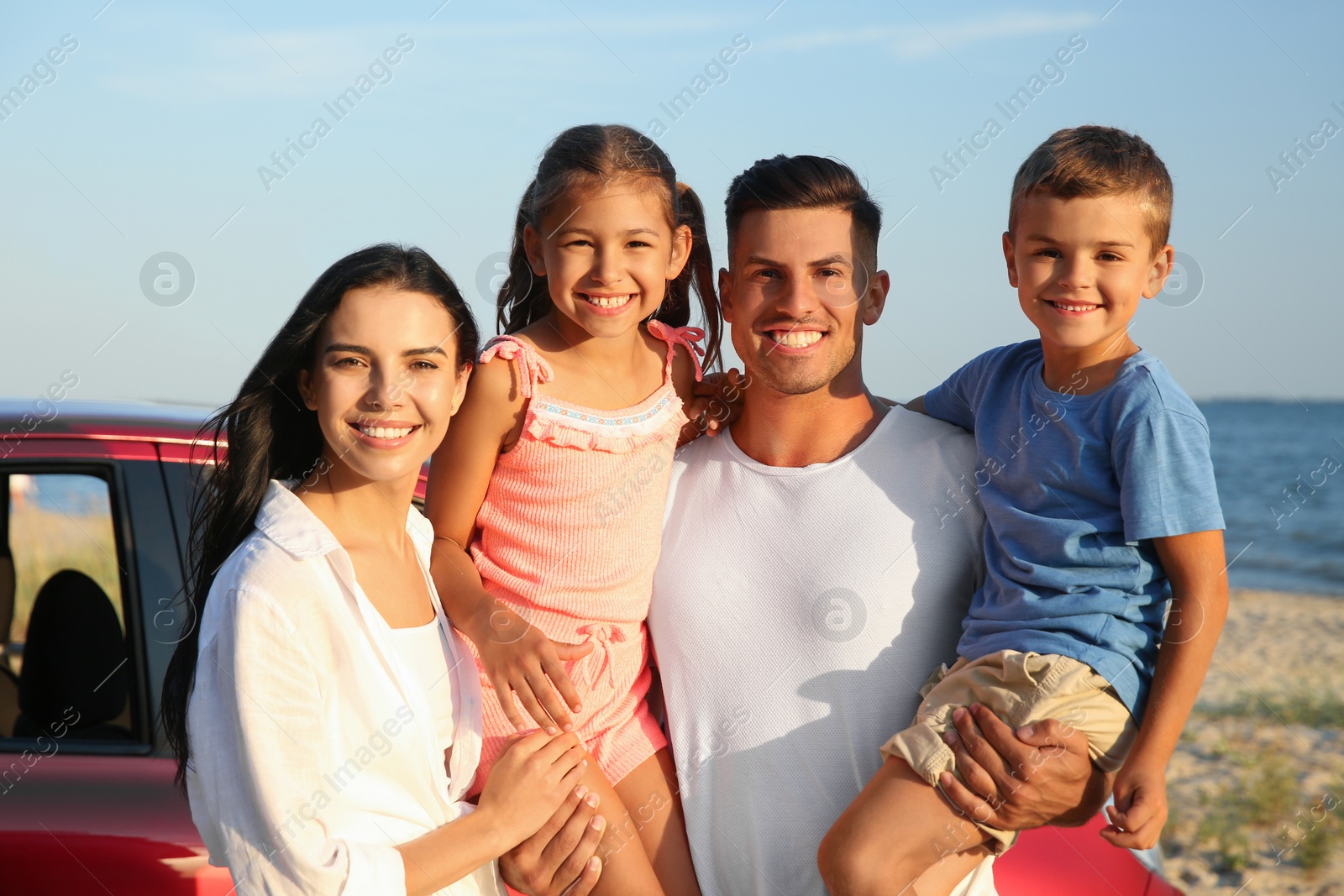 Photo of Happy family near car on beach. Summer trip