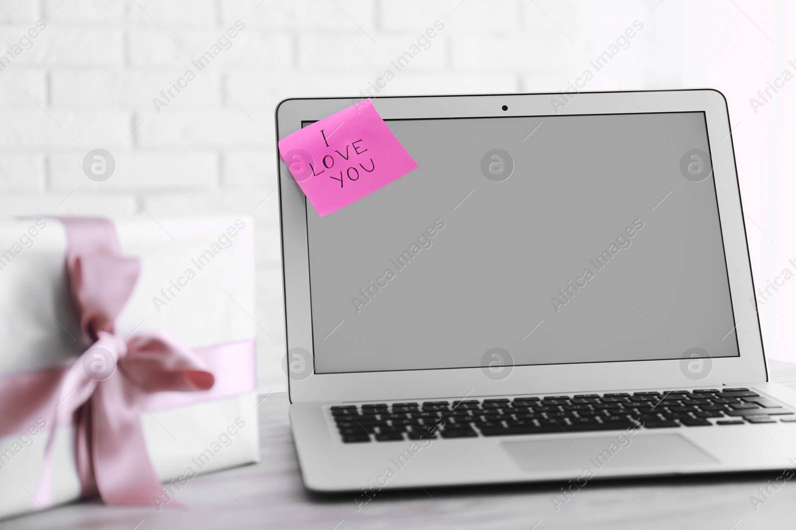 Photo of Memory sticker with phrase I Love You on laptop at table. Valentine's Day celebration