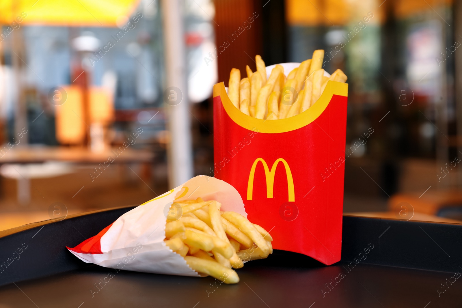 Photo of MYKOLAIV, UKRAINE - AUGUST 11, 2021: Big and small portions of McDonald's French fries on tray in cafe