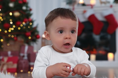 Photo of Portrait of cute baby with toy in room decorated for Christmas
