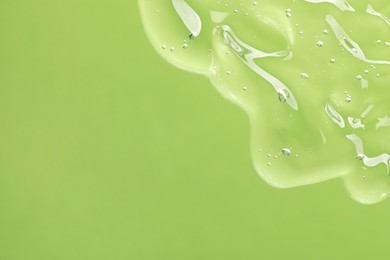 Photo of Transparent cleansing gel on green background, top view with space for text. Cosmetic product