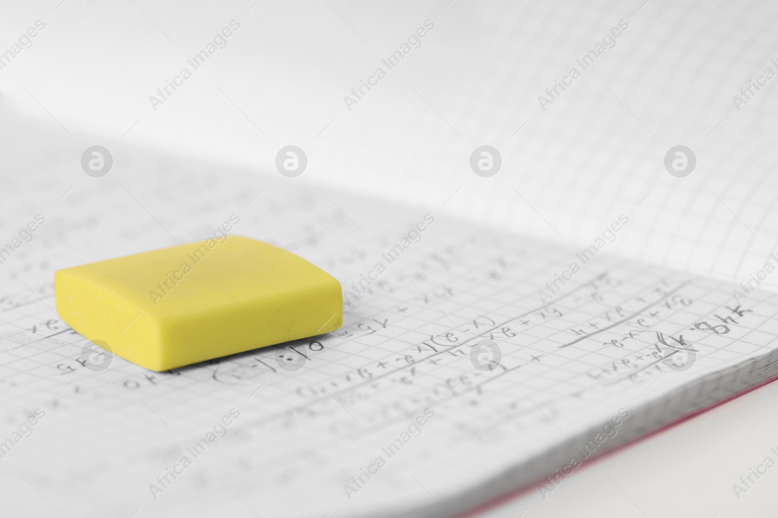 Photo of Yellow eraser and notebook on white desk, closeup. Space for text