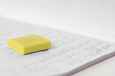 Yellow eraser and notebook on white desk, closeup. Space for text