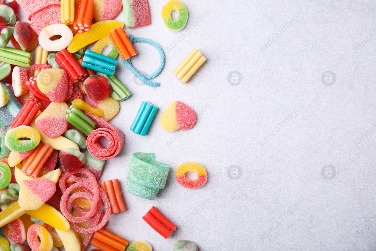 Photo of Many tasty colorful jelly candies on white table, flat lay. Space for text