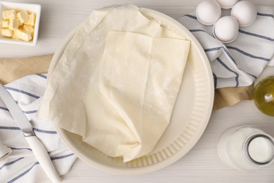 Fresh dough and different ingredients for making baklava on white wooden table, flat lay