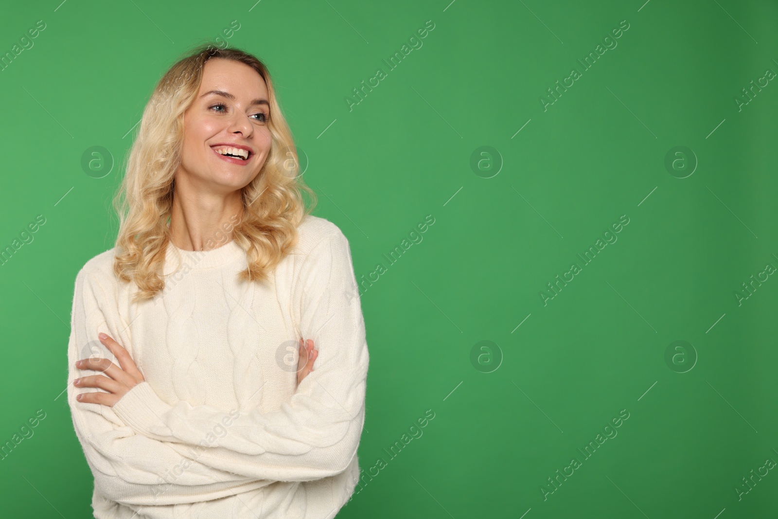 Photo of Happy woman in stylish warm sweater on green background. Space for text