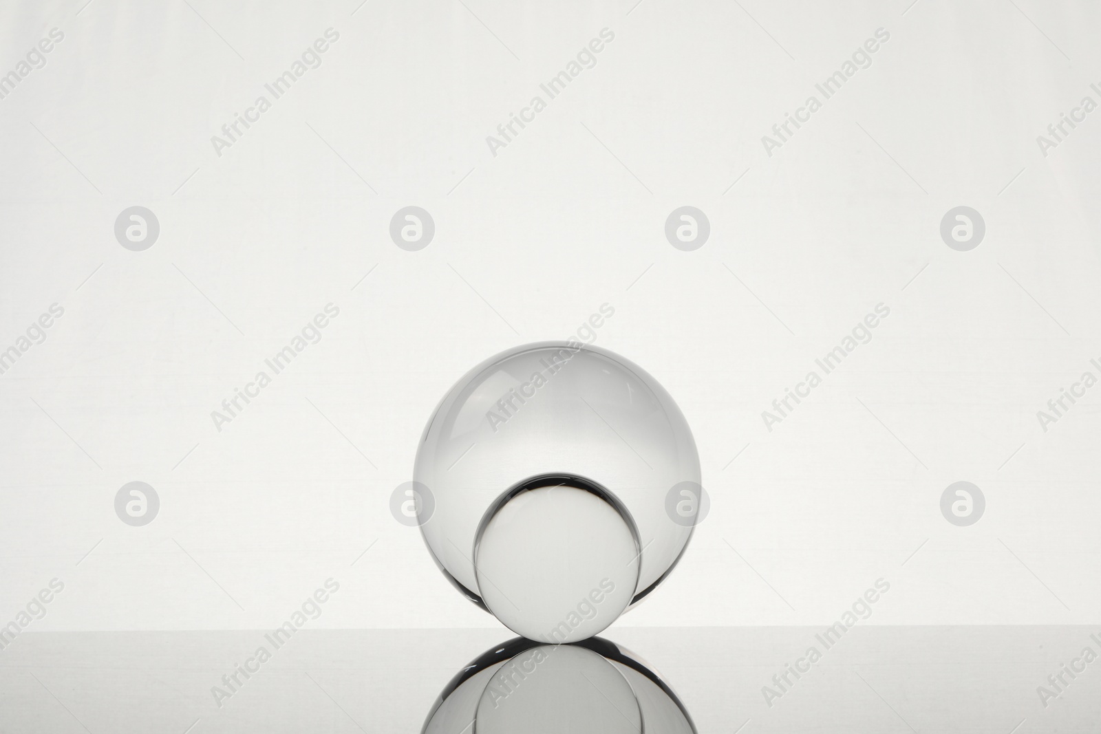 Photo of Transparent glass balls on mirror surface against light background