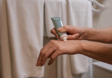 Photo of Woman applying hand cream in bathroom, closeup