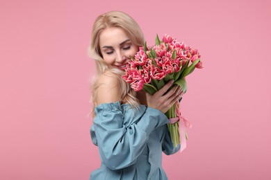 Happy young woman with beautiful bouquet on dusty pink background