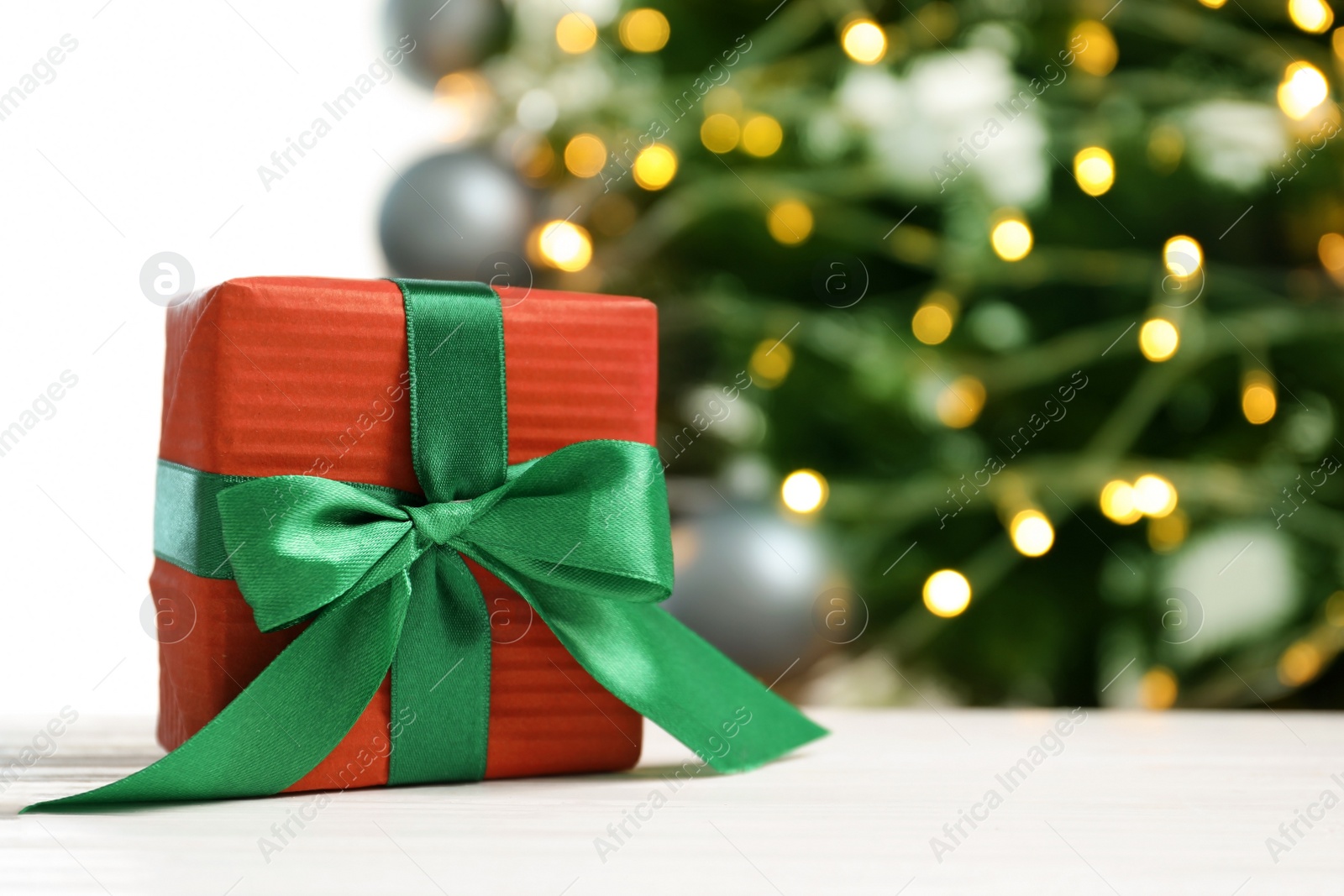 Photo of Beautiful gift box and blurred Christmas tree on background