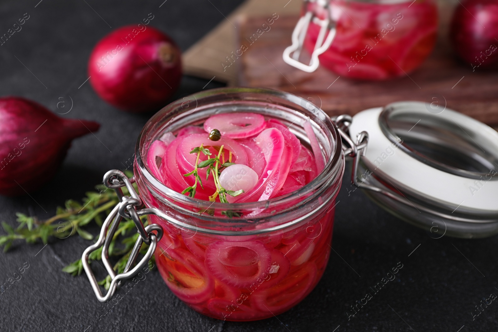 Photo of Jar with tasty pickled onions on black table