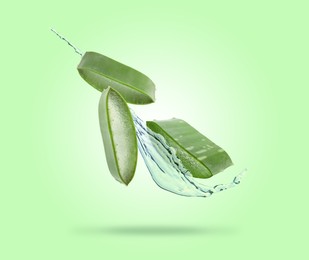 Image of Sliced aloe vera leaf and splash of juice on green background