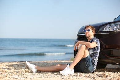 Photo of Young man near car on beach. Space for text