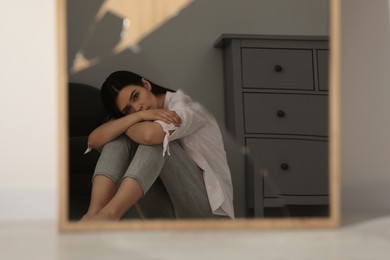 Mental problems. Depressed woman reflecting in broken mirror