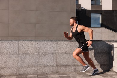Photo of Young man running near building outdoors. Space for text