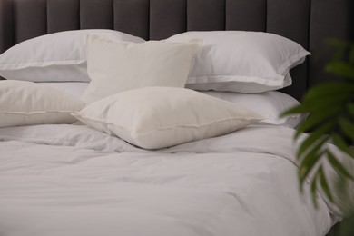 Photo of Many soft white pillows and duvet on bed indoors