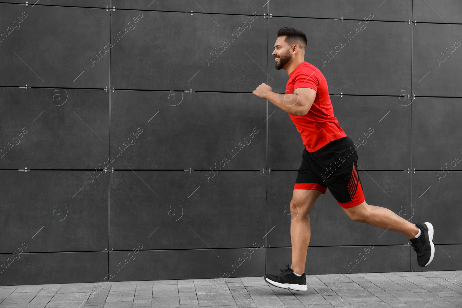 Photo of Happy man running near building outdoors. Space for text