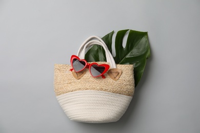 Photo of Stylish straw bag and sunglasses on grey background, flat lay. Summer accessories