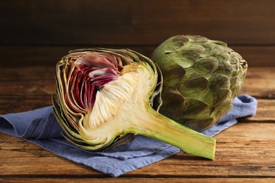 Cut and whole fresh raw artichokes on wooden table