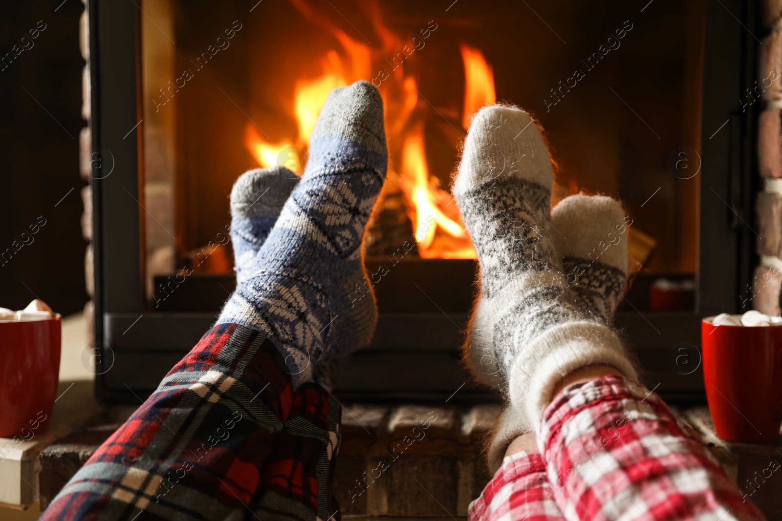 Photo of Couple in pajamas resting near fireplace indoors, closeup. Winter vacation