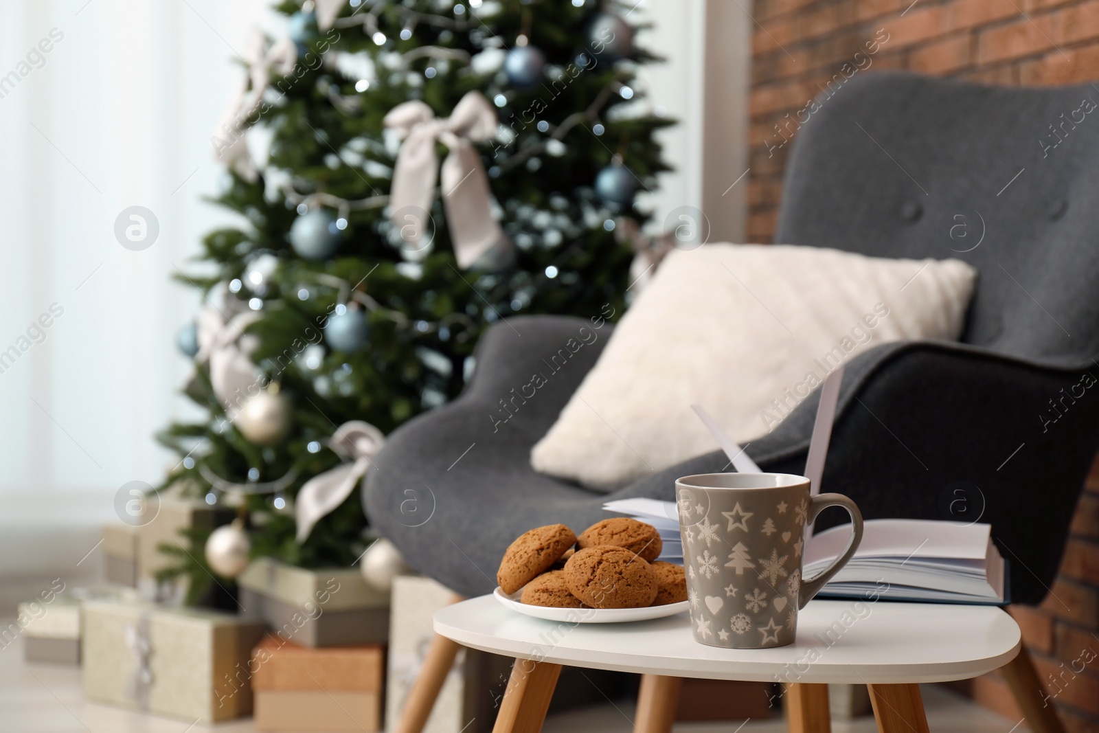 Photo of Book with treat on table and Christmas tree in stylish living room interior