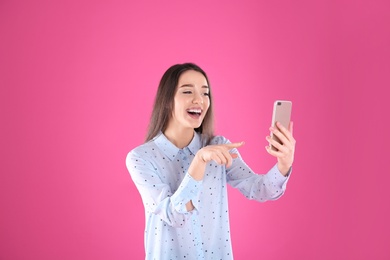 Woman using mobile phone for video chat on color background