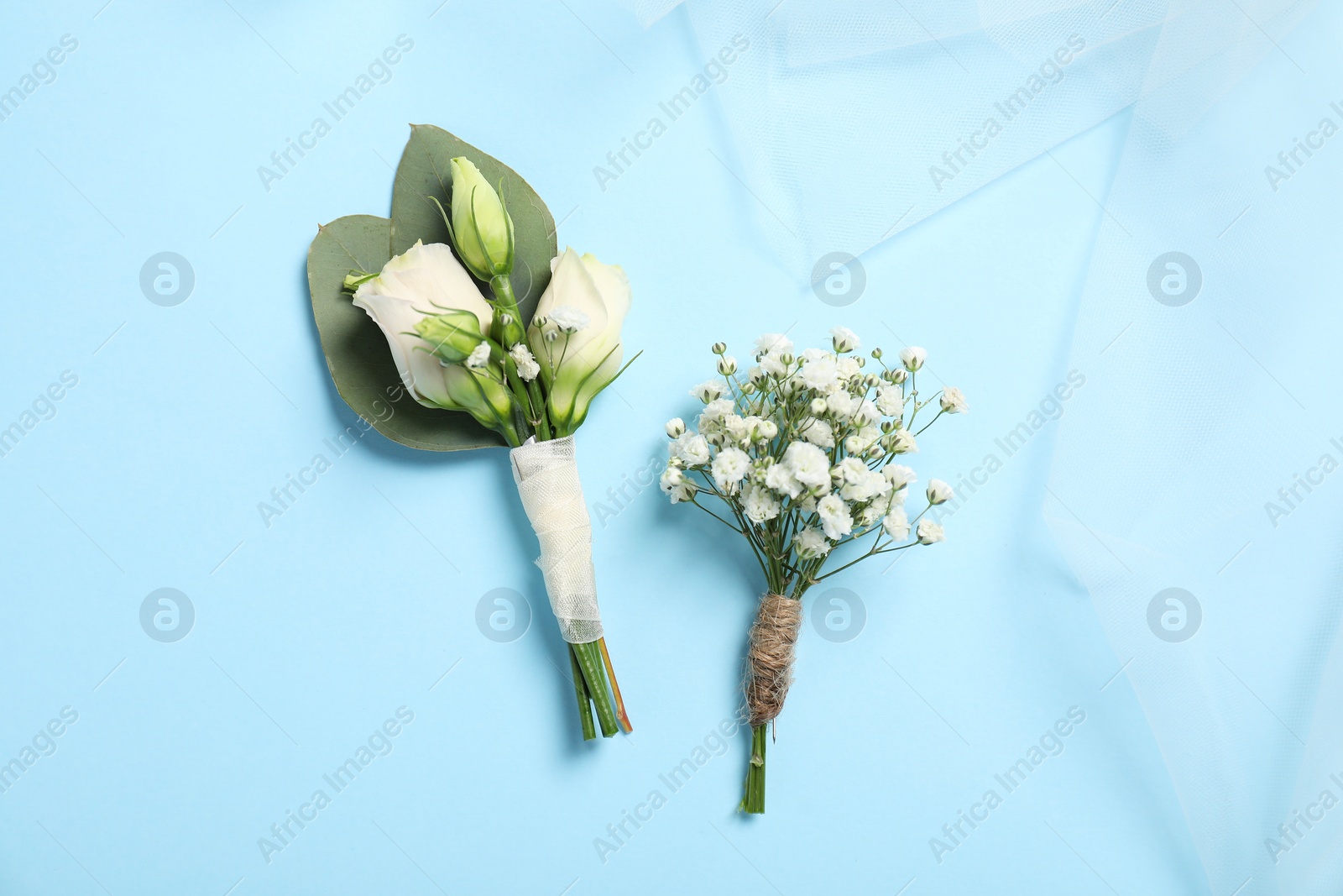 Photo of Wedding stuff. Stylish boutonnieres on light blue background, top view