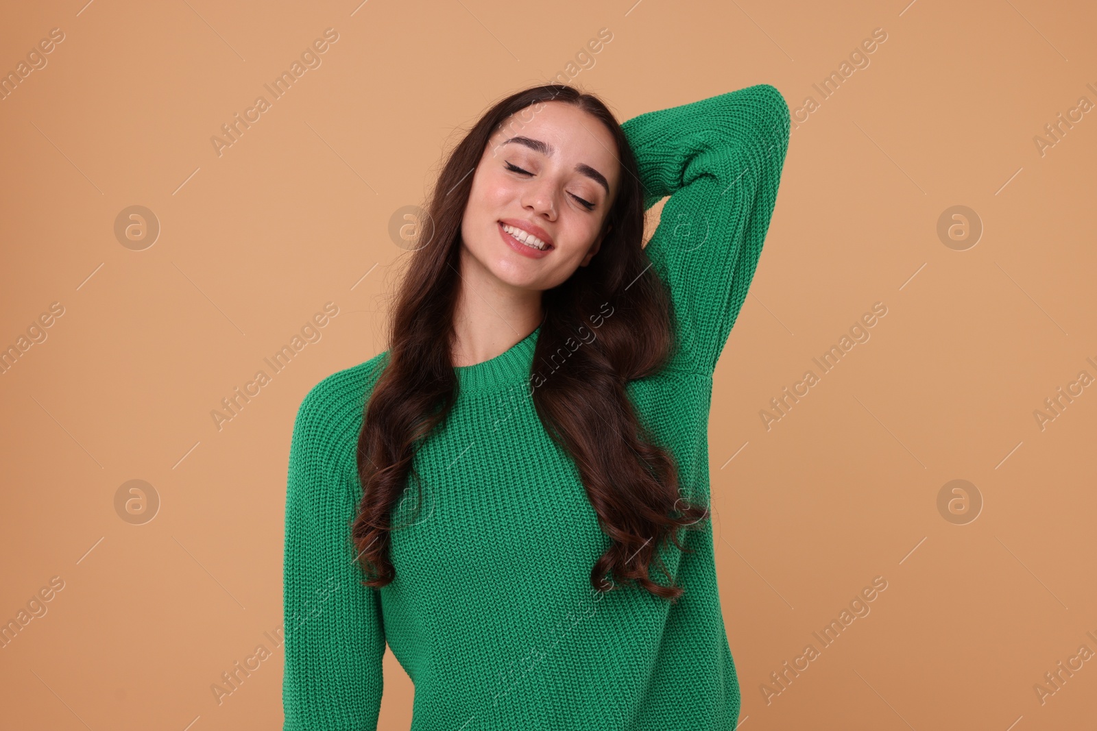 Photo of Beautiful young woman in stylish warm sweater on beige background