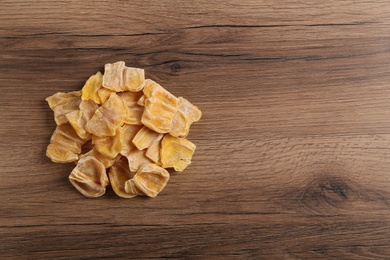 Delicious dried jackfruit slices on wooden table, top view. Space for text