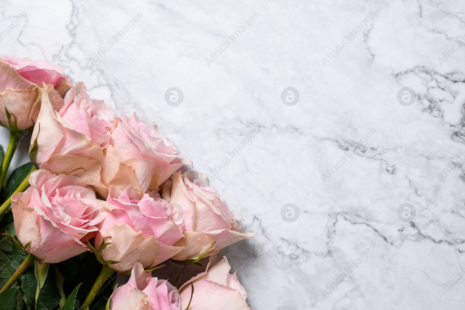 Photo of Beautiful bouquet of roses on white marble table, top view with space for text. Happy birthday greetings