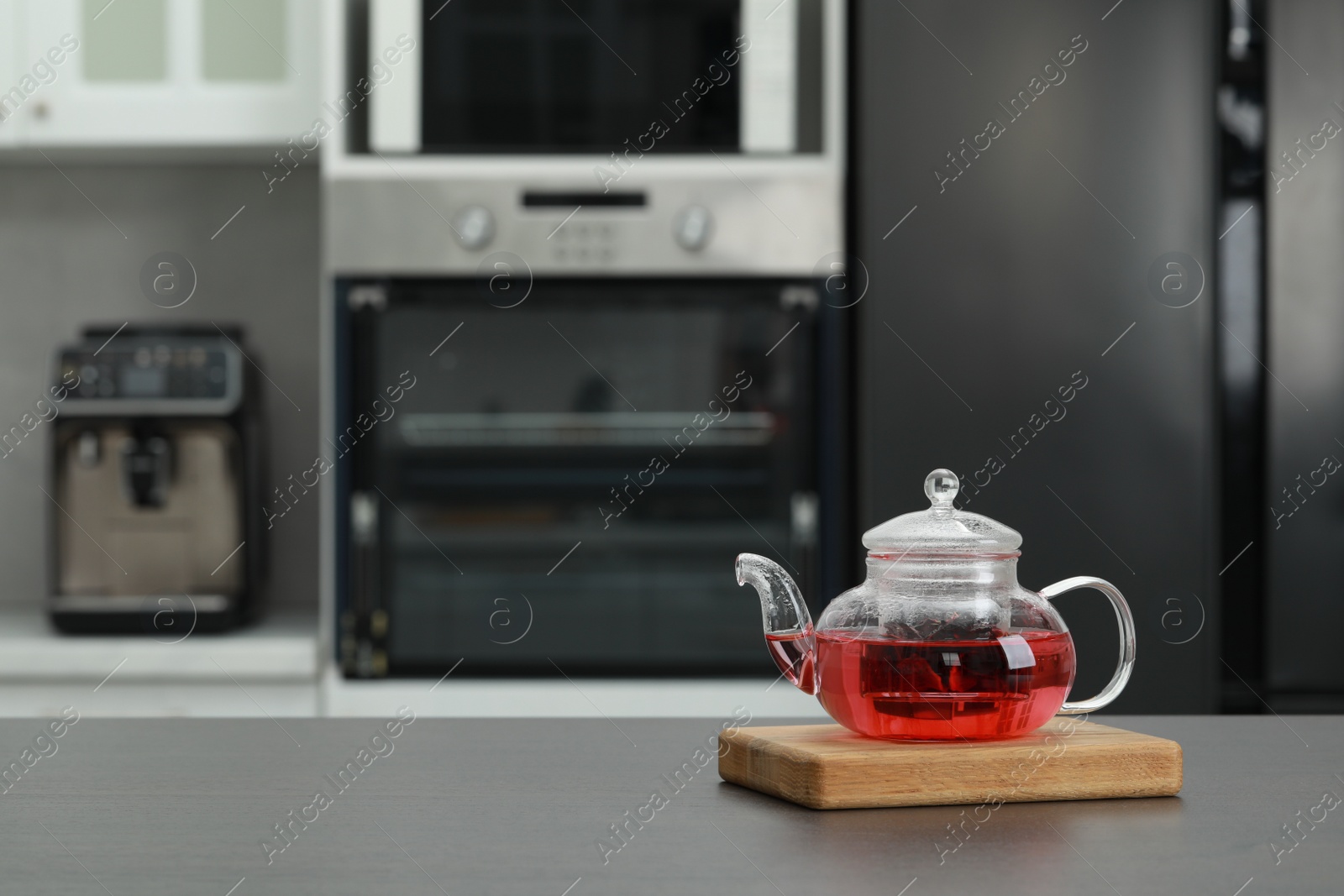Photo of Glass teapot with delicious tea on grey table in kitchen. Space for text