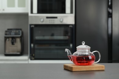 Photo of Glass teapot with delicious tea on grey table in kitchen. Space for text