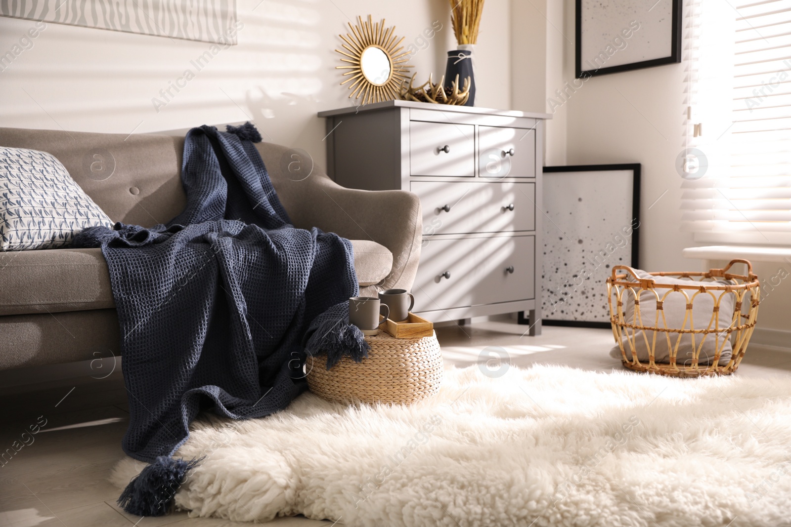 Photo of Comfortable sofa with soft plaid in stylish room interior