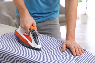 Man ironing shirt on board at home, closeup