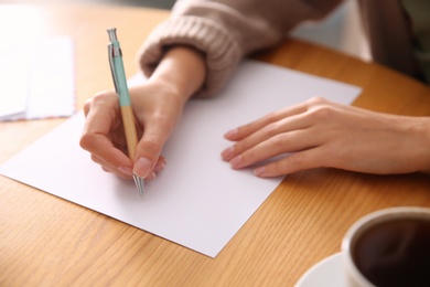 Photo of Woman writing letter at wooden table, closeup