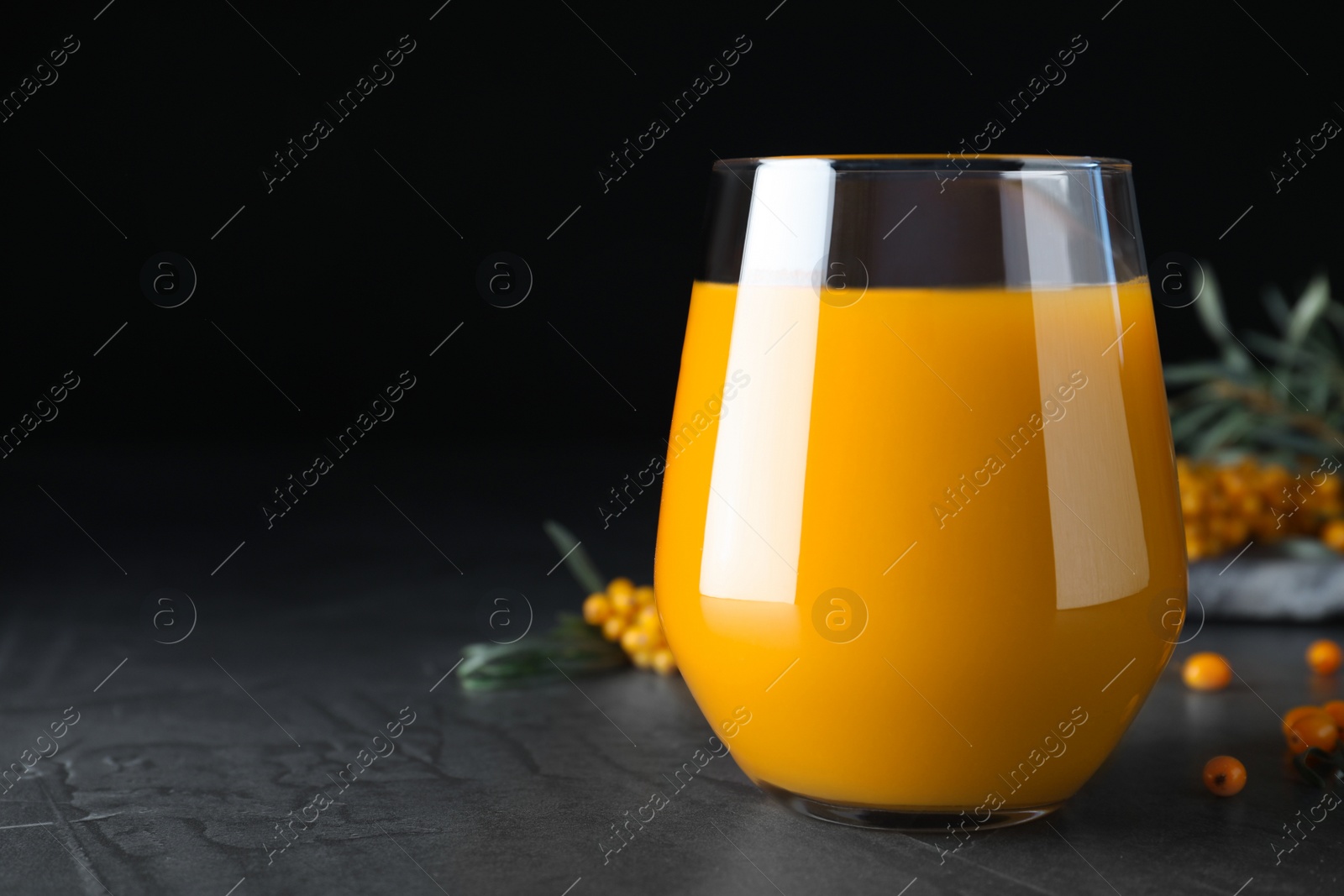 Photo of Sea buckthorn juice on black table, closeup. Space for text