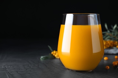 Photo of Sea buckthorn juice on black table, closeup. Space for text