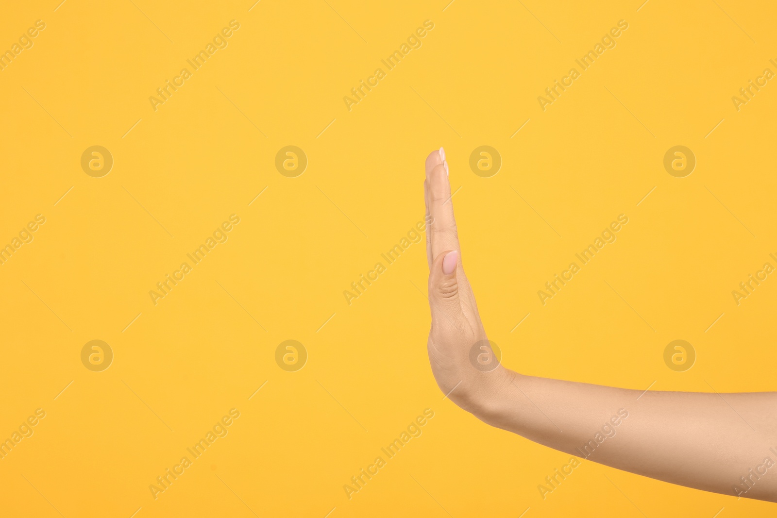 Photo of Woman showing stop gesture on orange background, closeup. Space for text