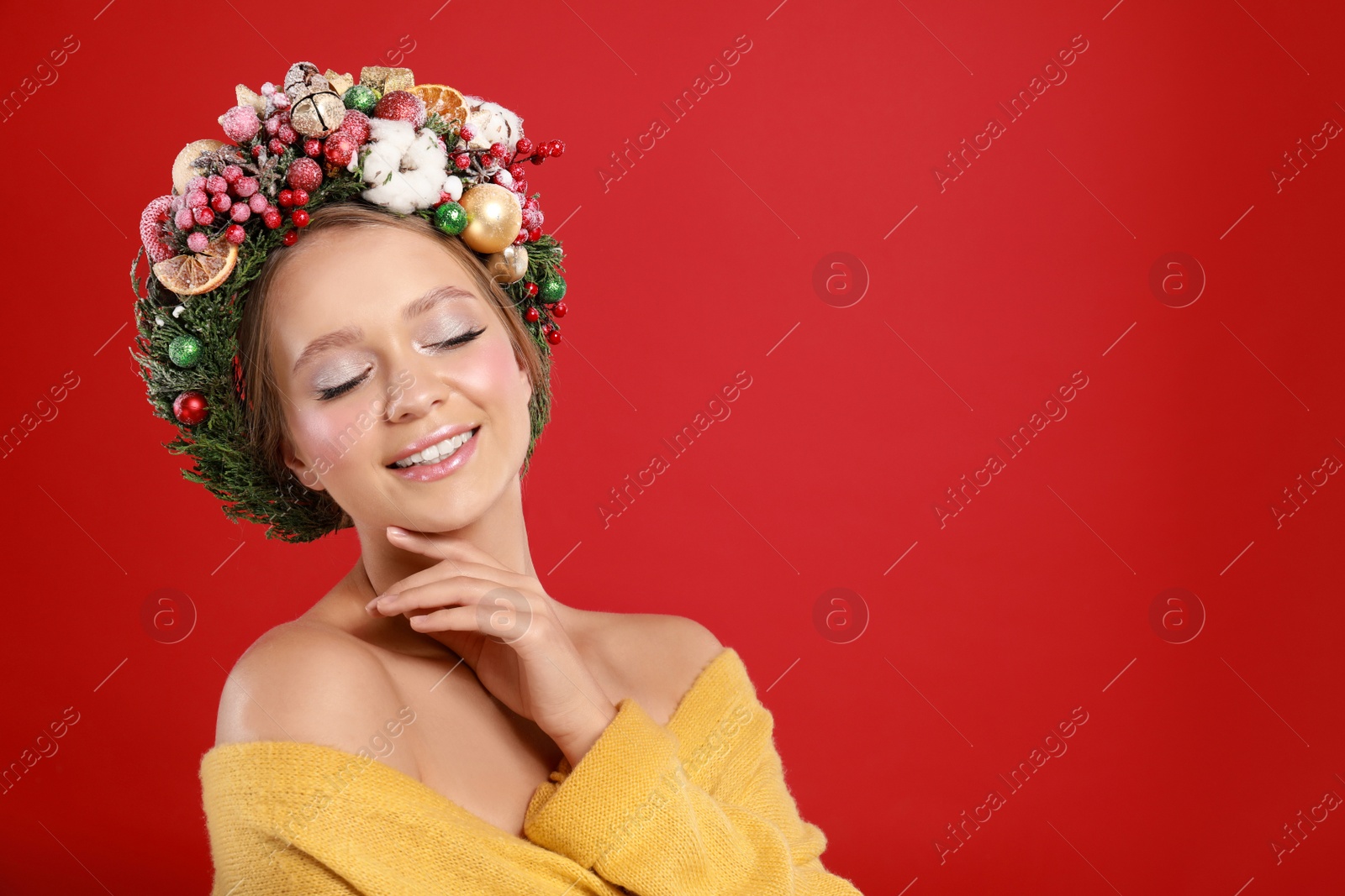 Photo of Beautiful young woman wearing Christmas wreath on red background. Space for text