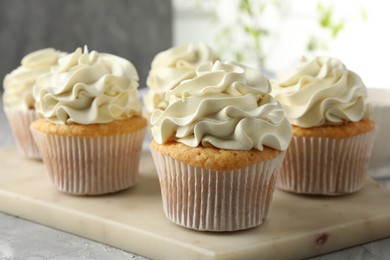 Photo of Tasty cupcakes with vanilla cream on grey table, closeup