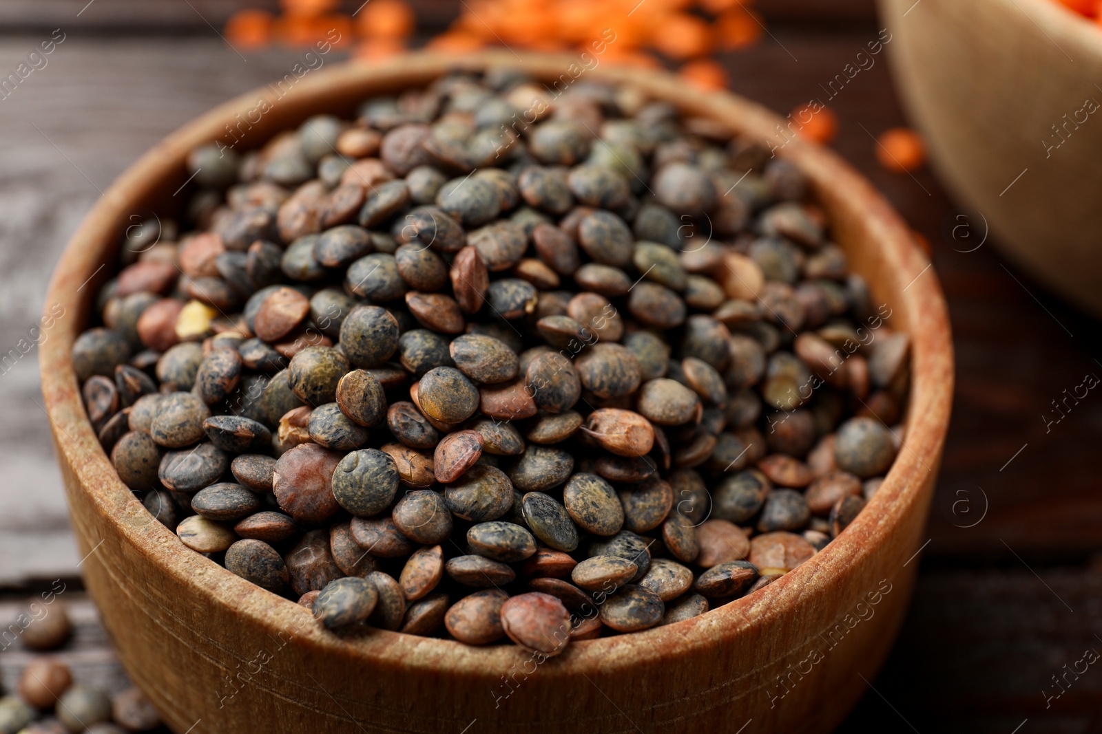 Photo of Raw lentils in bowl on table, closeup