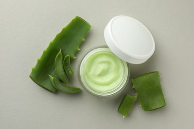 Jar with cream and cut aloe leaves on light grey background, flat lay