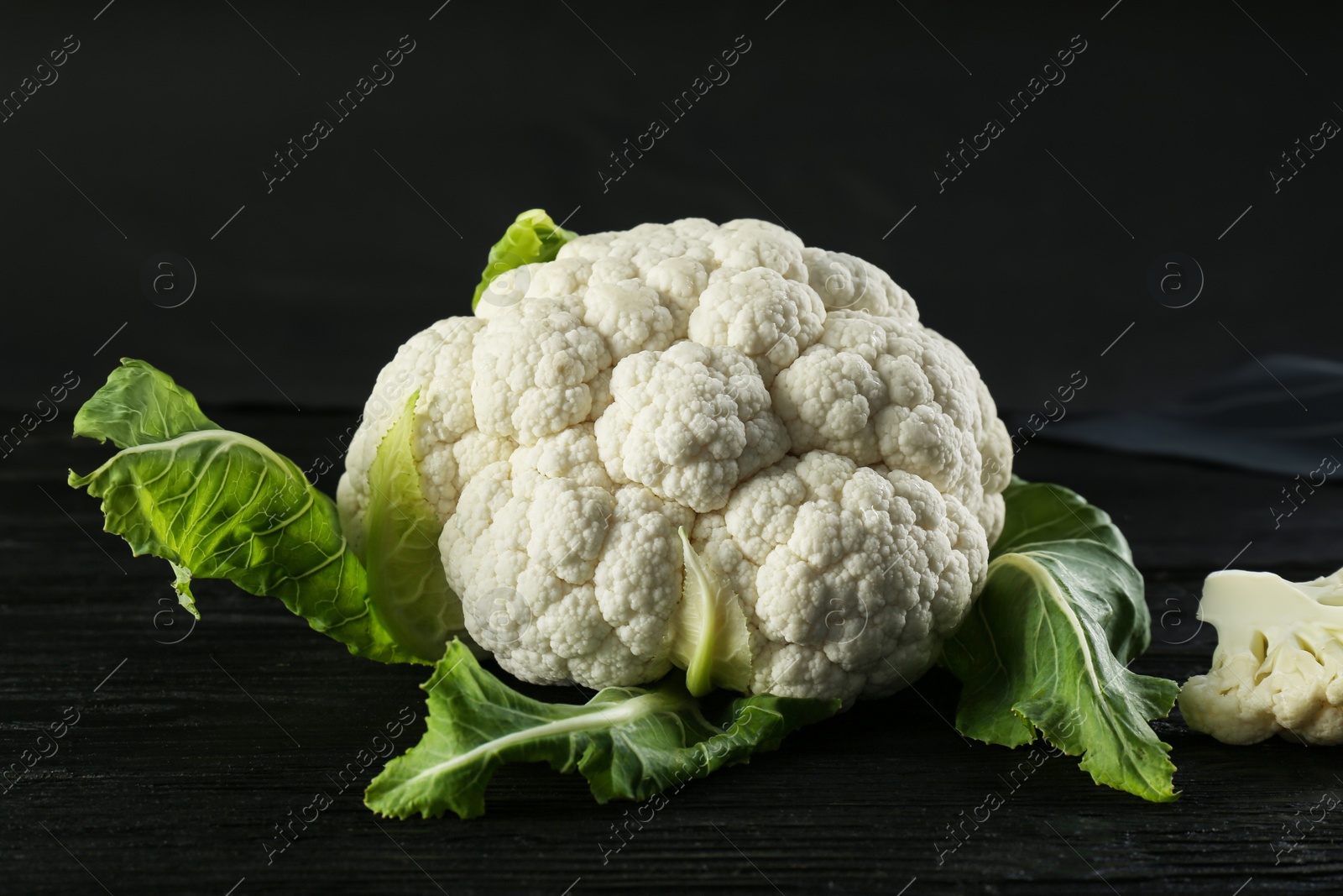 Photo of Fresh whole cauliflower on black wooden table