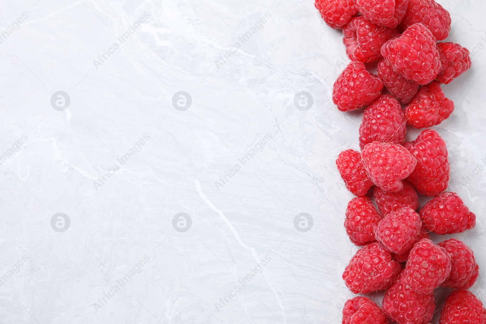 Photo of Delicious fresh ripe raspberries on light marble table, flat lay. Space for text