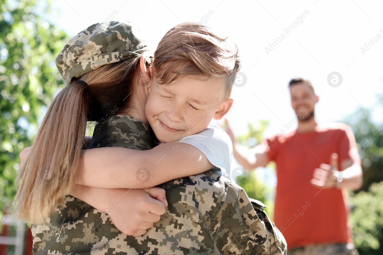 Photo of Female soldier hugging with her son outdoors. Military service