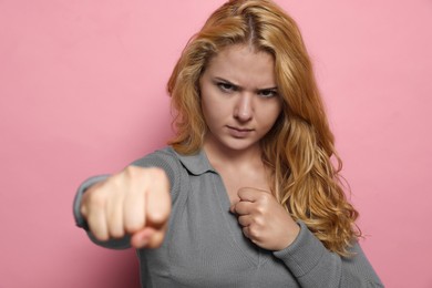 Photo of Angry young woman ready to fight on pink background