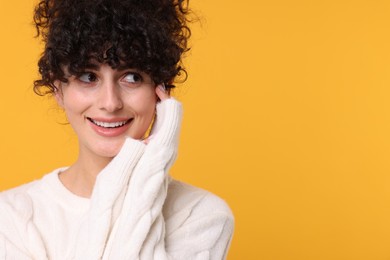 Photo of Happy young woman in stylish white sweater on yellow background, space for text