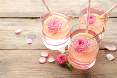 Refreshing drink with lemon and rose on wooden table