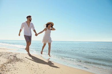 Happy young couple running on beach near sea. Honeymoon trip